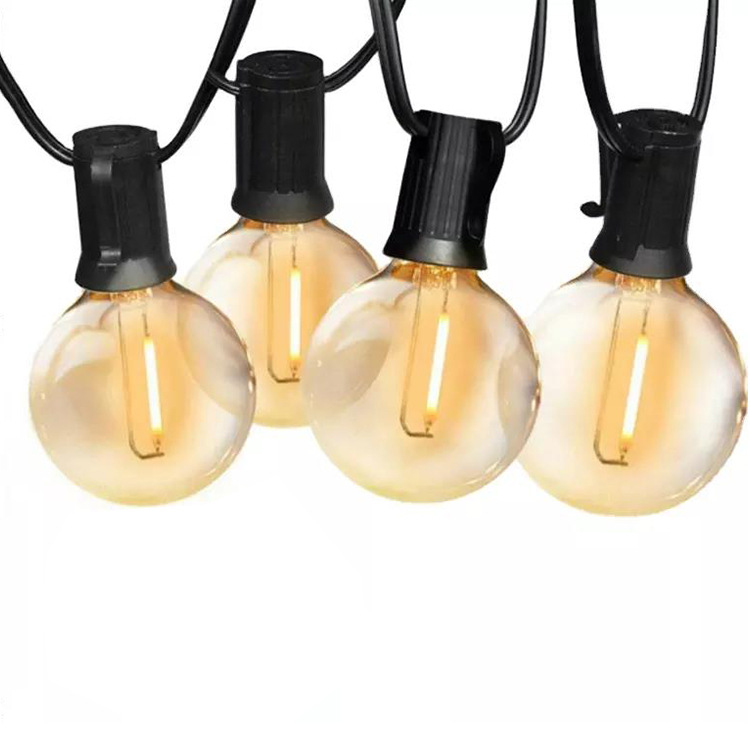 Four illuminated globe bulbs in black sockets on a black cable